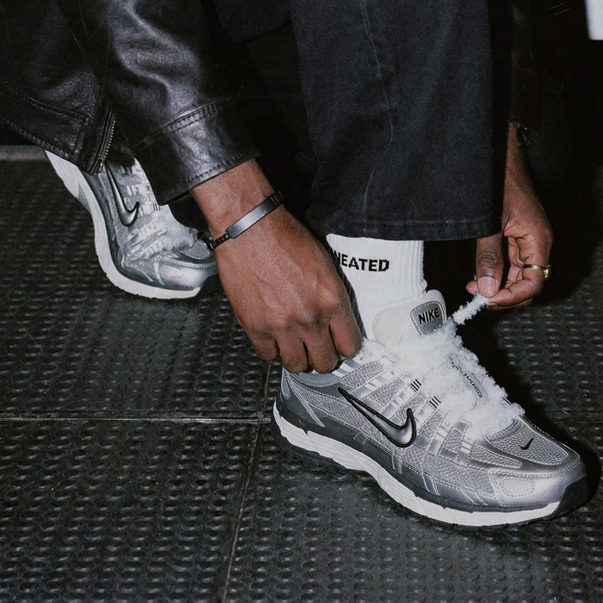 Person zieht weiße SNEATED Fuzzy Laces an Sneakern fest - flauschige Sneaker Laces