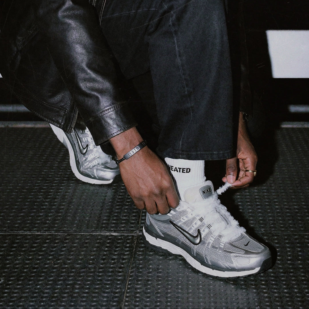 Person zieht weiße SNEATED Fuzzy Laces an Sneakern fest - flauschige Sneaker Laces